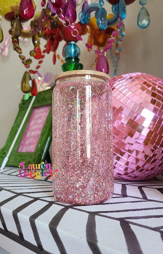 a pink glitter jar sitting on top of a table next to a disco ball and other decorations