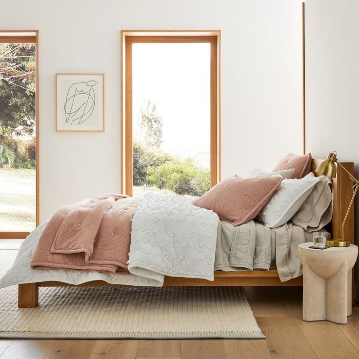 a bedroom with white walls and wooden flooring has a large window overlooking the field