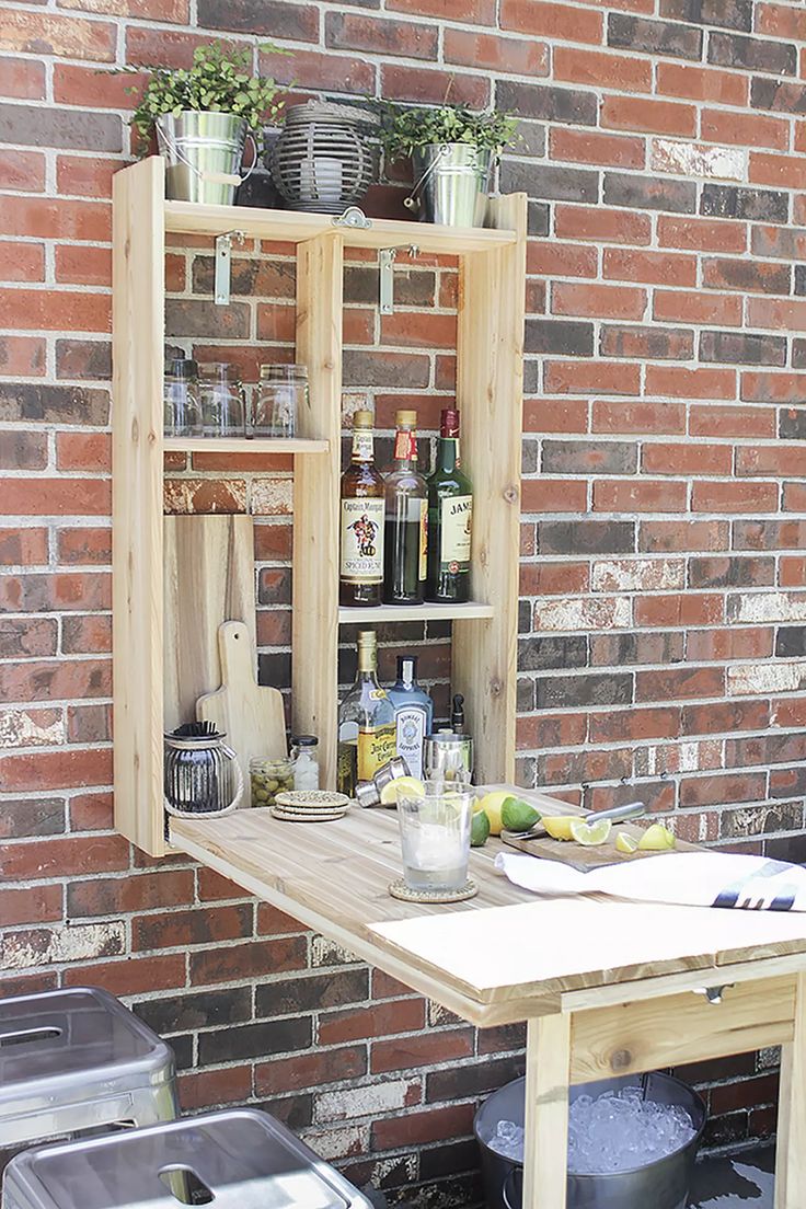 an outdoor table with pots and pans on it, next to a brick wall