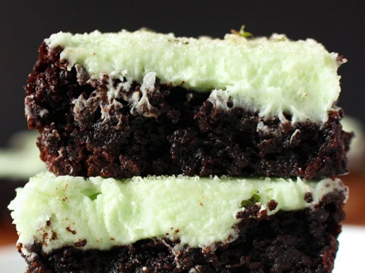 two chocolate brownies with green frosting stacked on top of each other