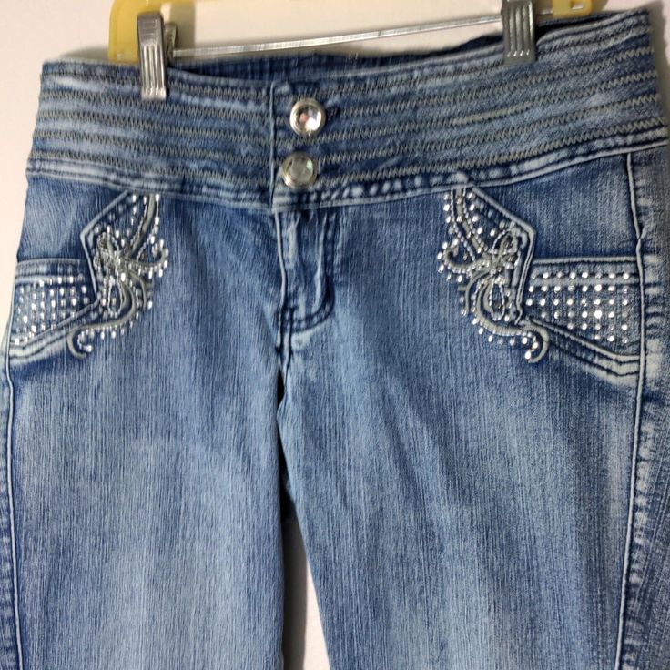 Cotton And 3 Percent Spandex Mid Rise Jeans With A Double Rhinestone Buttoned 3" Waist Band. Skinny Style With 2 Small Front Watch Pockets In The Front Design Of Small Rhinestones. Studs And Embroidery. Embellished Back Pockets And Trim On Back Waist Band. Measurements For Size 9- Waist 29, Front Rise 8, Inseam 31, Ankle 12. Fitted Mid-rise Jeans With Rhinestones, Trendy Fitted Jeans With Rhinestones, Casual Fitted Jeans With Rhinestones, Fitted Casual Jeans With Rhinestones, Fitted Summer Jeans With Rhinestones, Summer Fitted Jeans With Rhinestones, Trendy Fitted Embellished Bottoms, Trendy Embellished Fitted Bottoms, Fitted Rhinestone Jeans For Summer