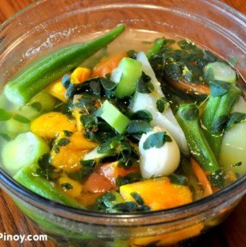 a glass bowl filled with vegetables on top of a wooden table