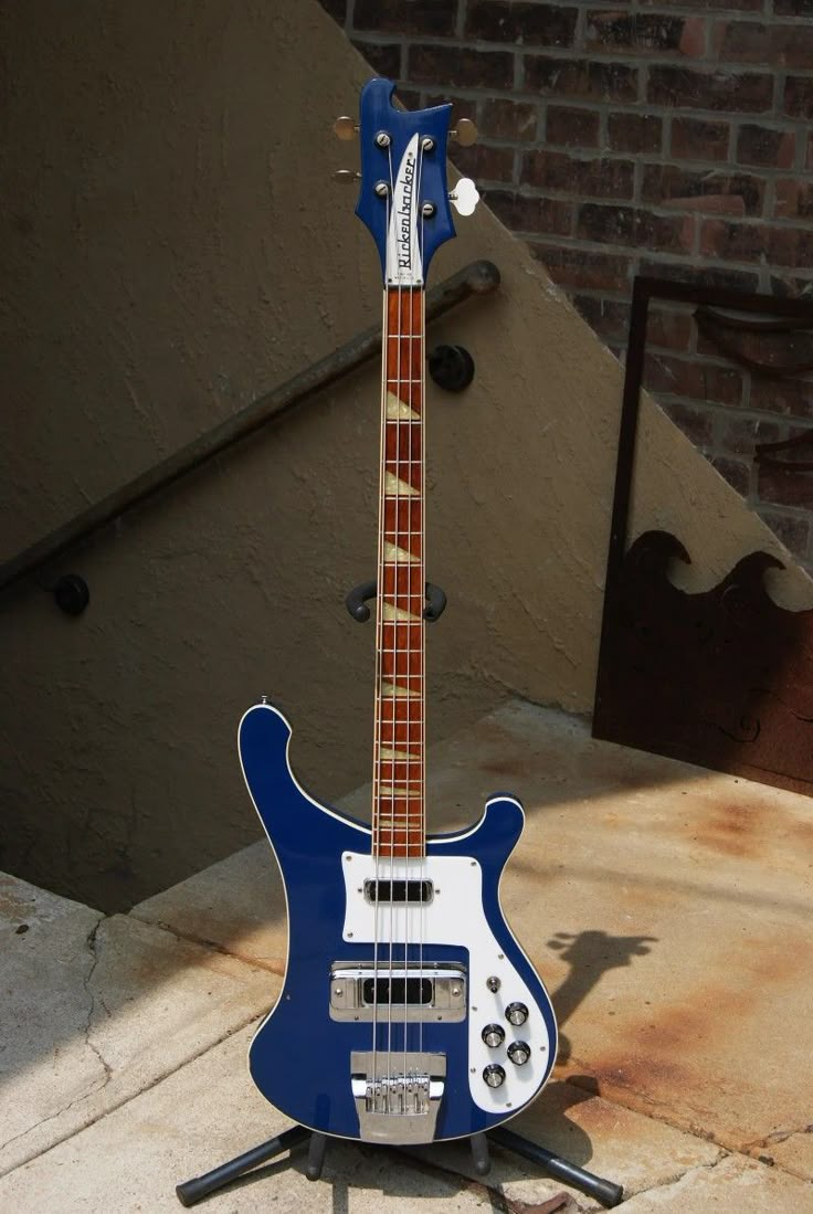 a blue and white electric guitar sitting on top of a wooden stand next to a brick wall