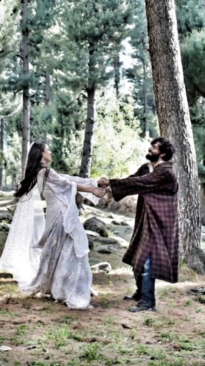 a man and woman are holding hands in the woods, one is dressed like a medieval princess