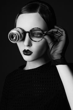 a woman in black and white is holding a pair of glasses