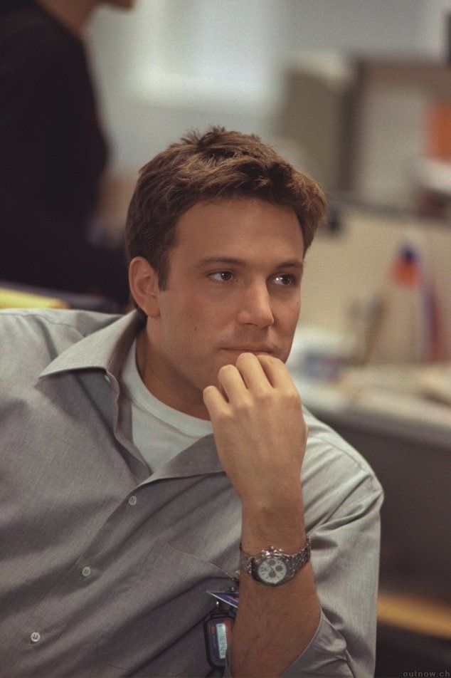 a man sitting in an office chair with his hand on his chin looking at the camera