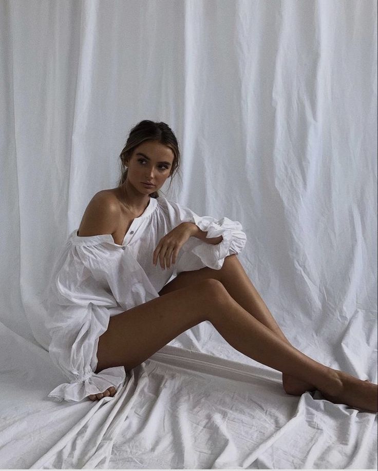 a woman sitting on top of a white sheet