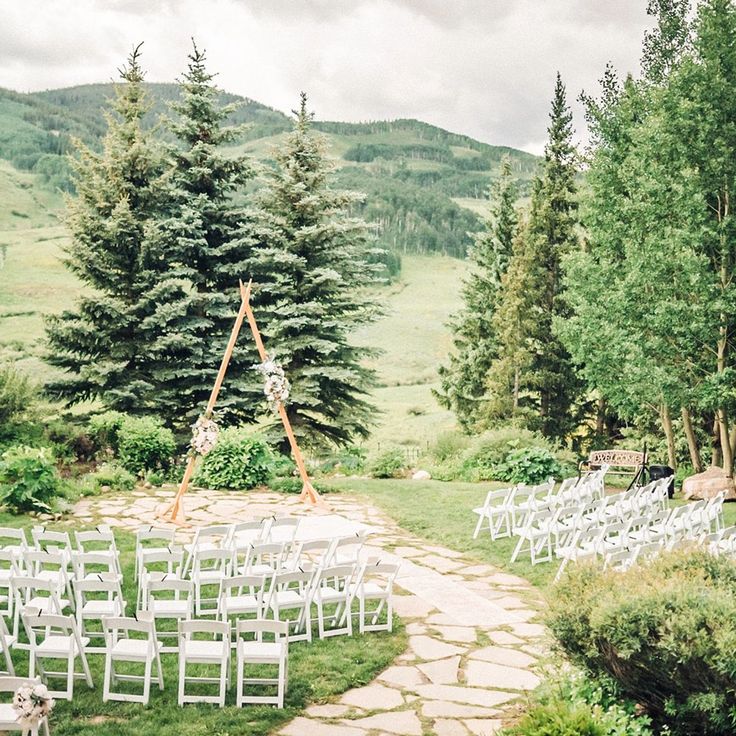 an outdoor ceremony set up with white chairs