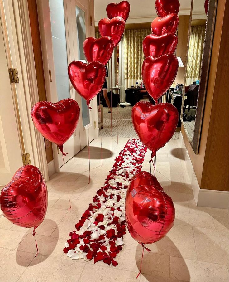 red heart shaped balloons floating in the air on a white carpeted hallway leading to an entrance