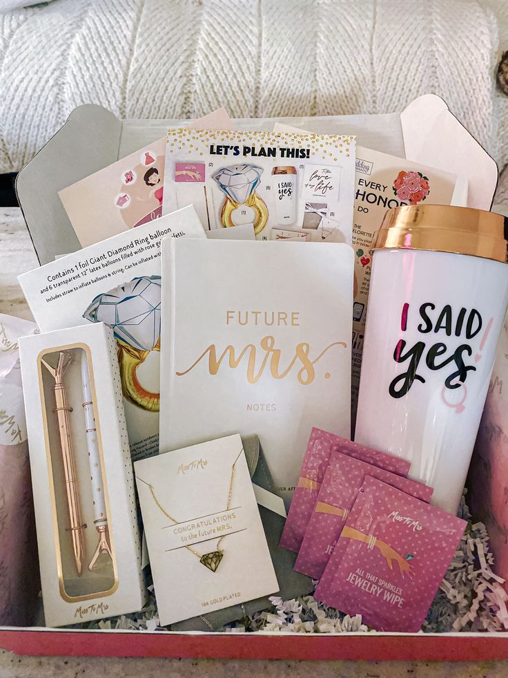 a pink box filled with lots of different types of cards and other items on top of a bed