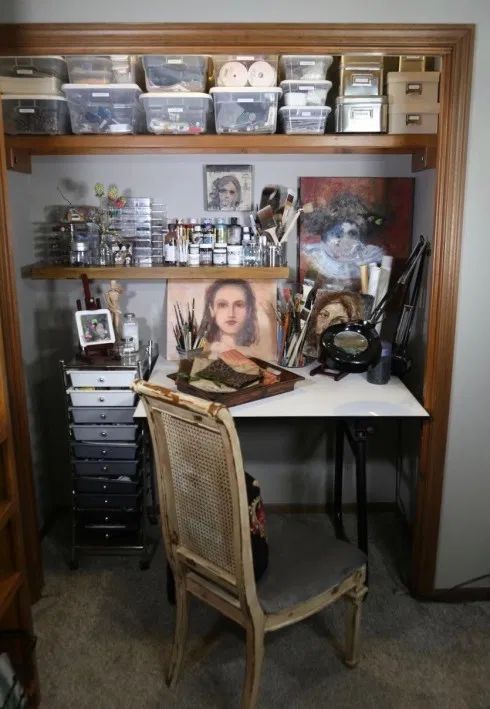 a desk with many items on it in front of a book shelf filled with books