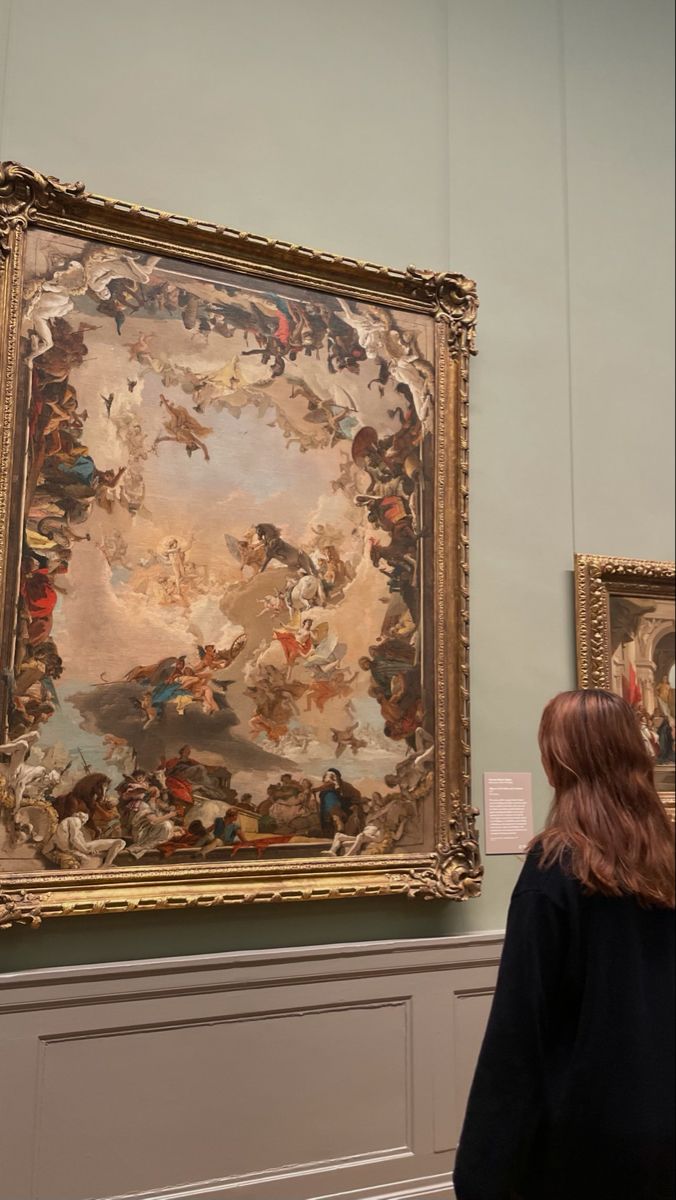 a woman standing in front of a large painting on display at a museum with people looking at it