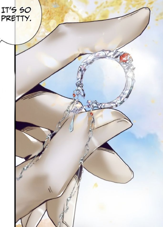 a hand holding a chain with a ring hanging from it's middle finger, in front of a blue sky and clouds