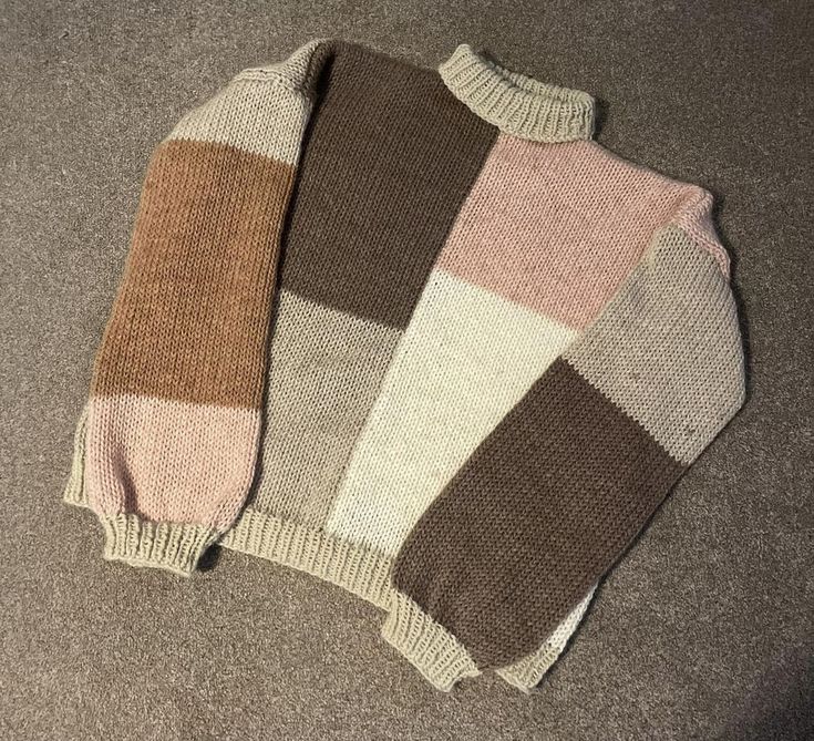 two sweaters sitting on the floor next to each other, one is brown and white