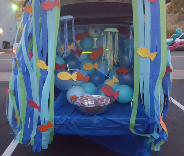 the trunk of a car decorated with blue and green balloons, streamers and decorations