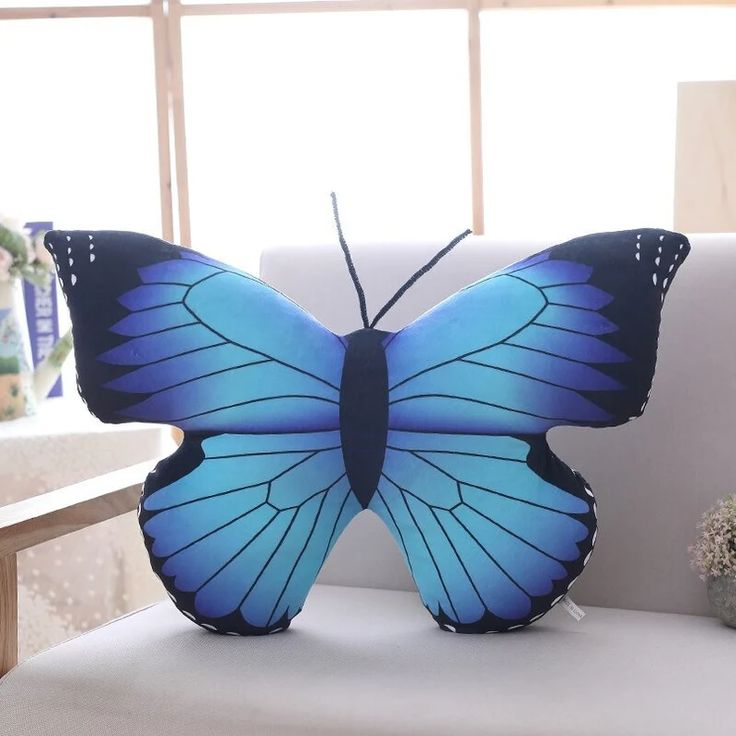 a blue butterfly pillow sitting on top of a white couch