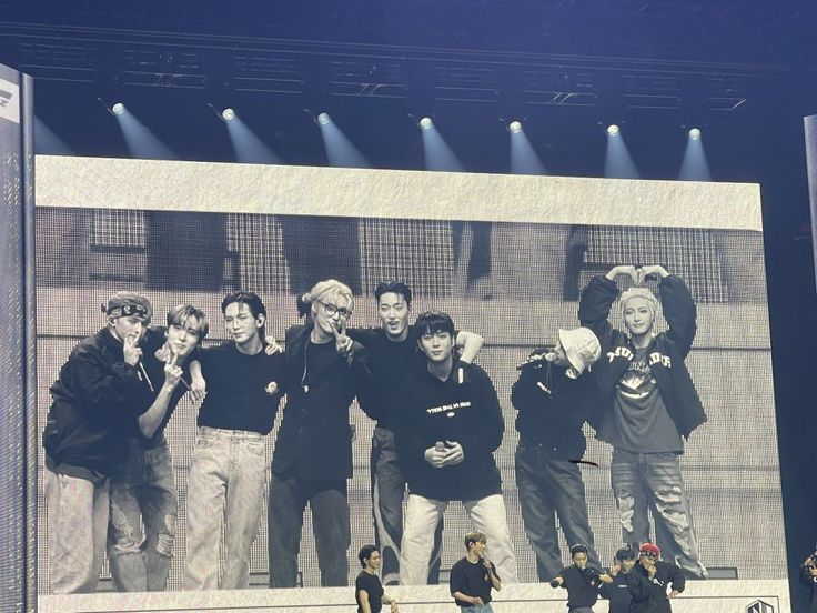 a group of people standing next to each other on top of a stage with lights