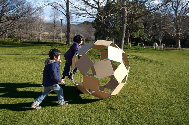 two children are playing with a large object in the grass