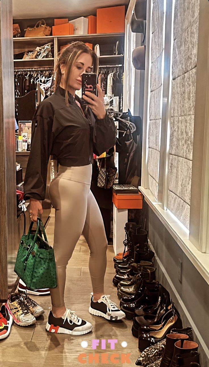 a woman taking a selfie in front of a closet full of shoes and handbags