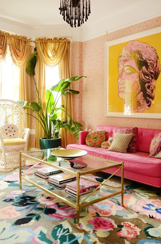 a living room with pink couches and paintings on the wall above them, along with colorful rugs