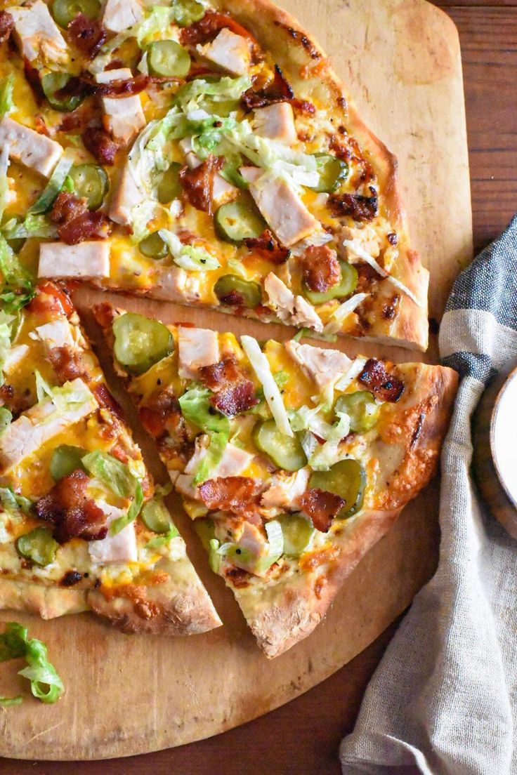 a pizza with many toppings on a cutting board