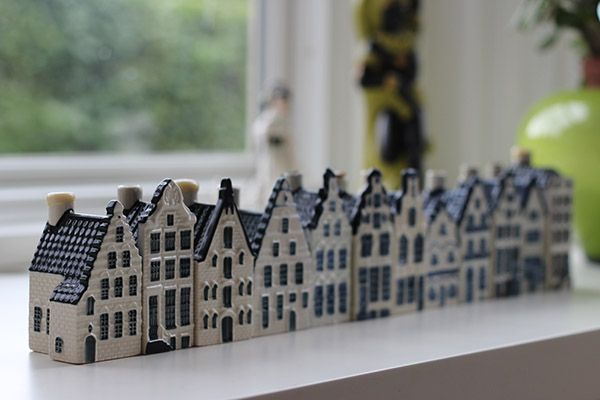 a row of small houses sitting on top of a table next to a vase with flowers