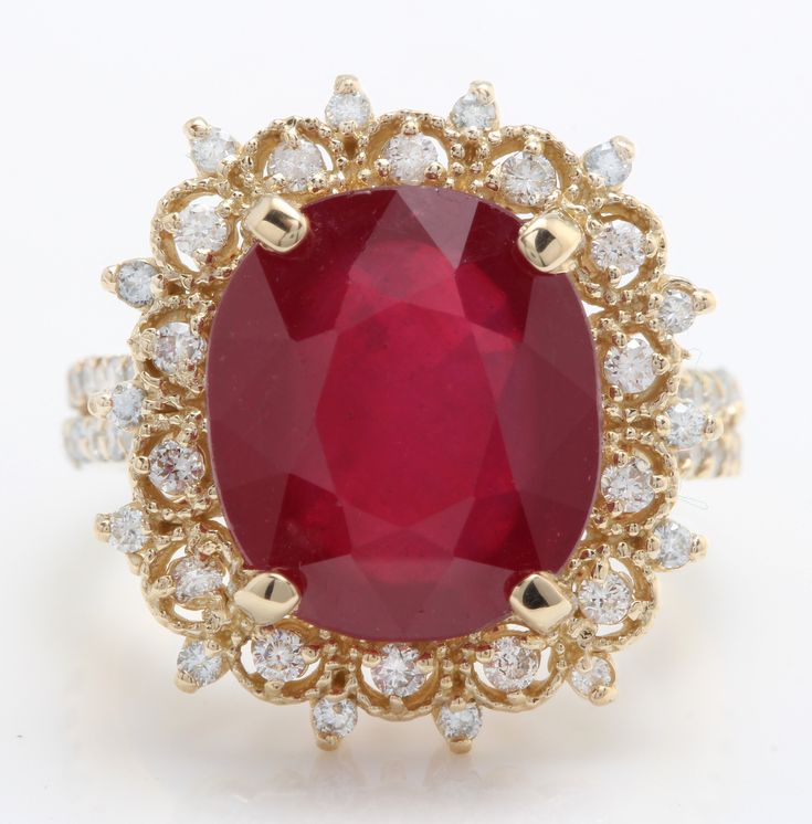 an oval shaped red stone surrounded by white and yellow diamonds in a gold ring with diamond accents