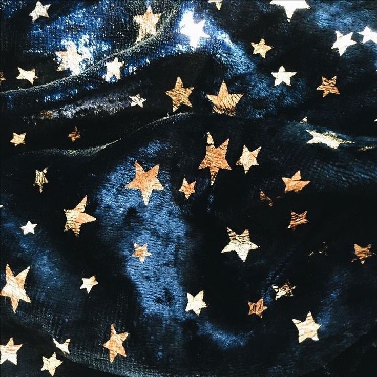 gold stars on black velvet fabric with white and blue background, closeup shot from the neck down