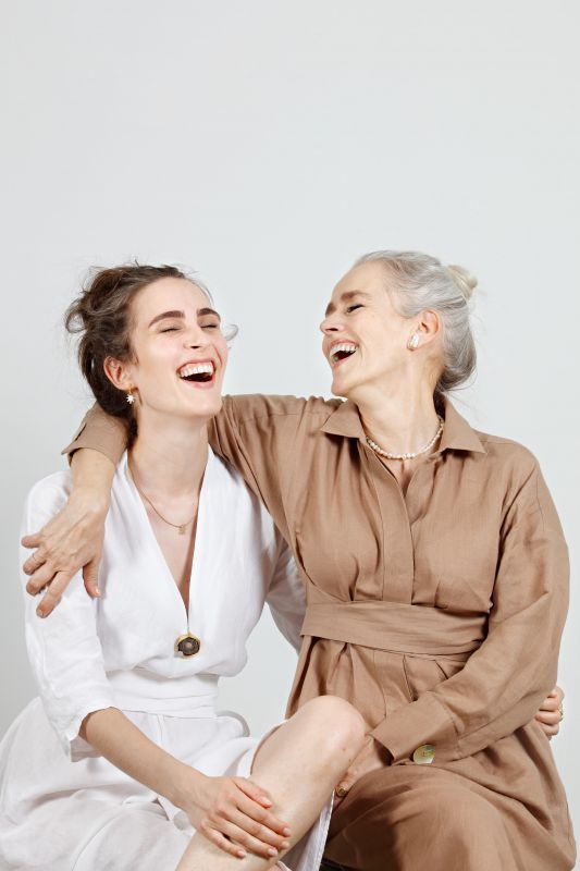 two women sitting next to each other laughing