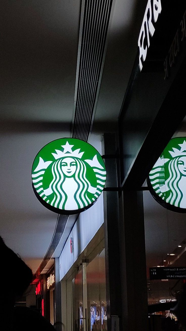 two starbucks signs hanging from the side of a building