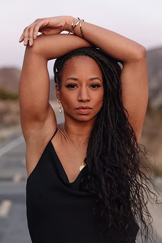 a woman with long hair standing in the middle of an empty road and holding her hands on her head