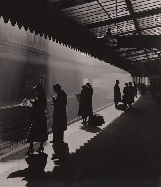 black and white photograph of people waiting at a train station