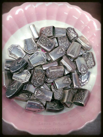 a pink and white bowl filled with lots of silver colored metal pieces on top of a table