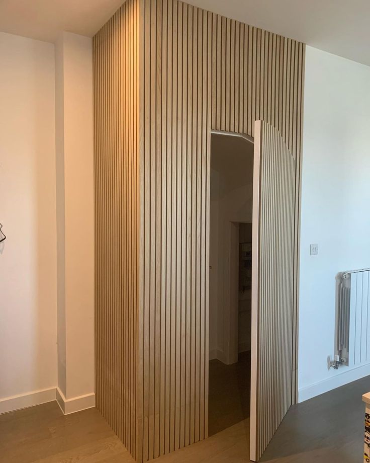 an empty room with wooden slats on the wall and a radiator in the corner