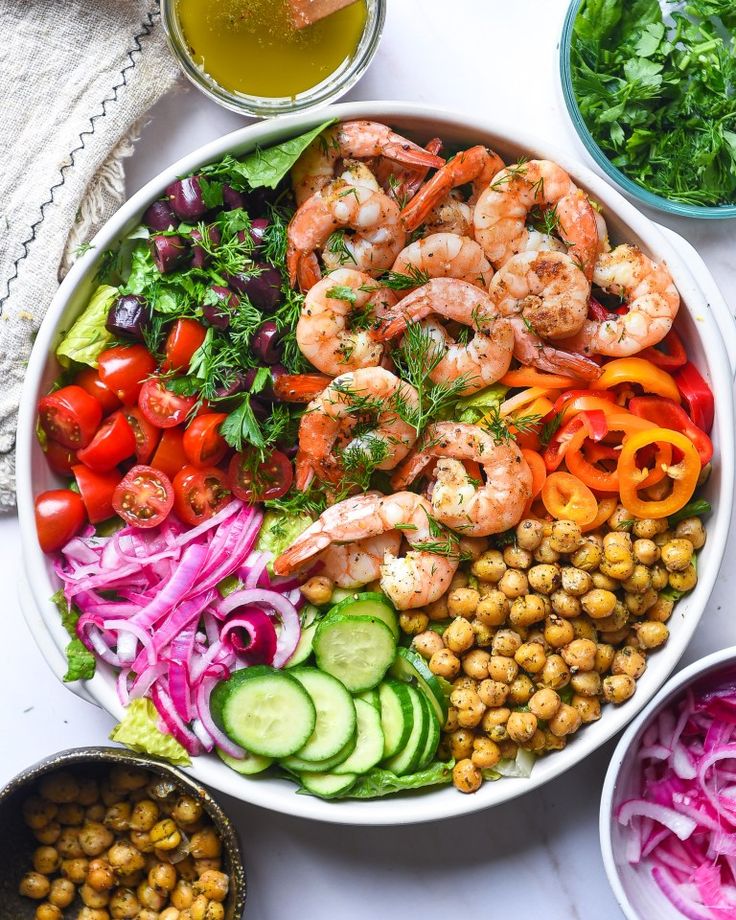 a bowl filled with shrimp, vegetables and dressing