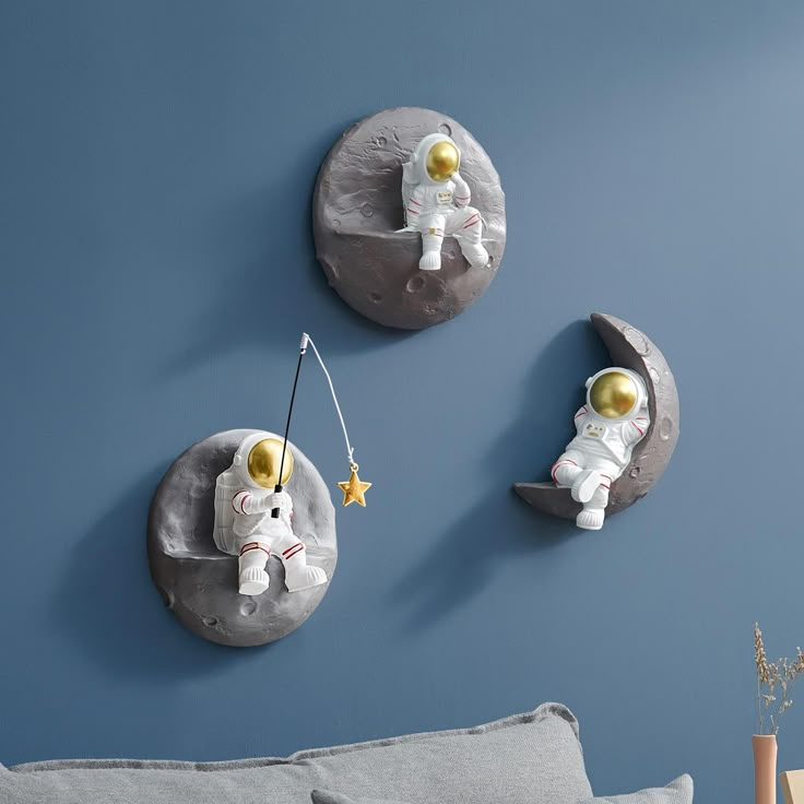 two moon shaped clocks are hanging on the wall next to a couch with a teddy bear