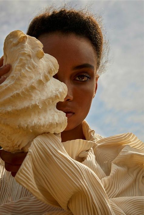 a woman holding up a piece of food to her face and looking at the camera