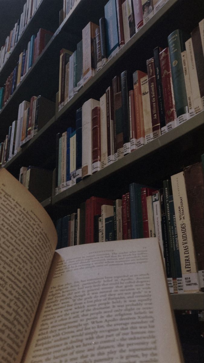 an open book sitting on top of a table in front of a bookshelf