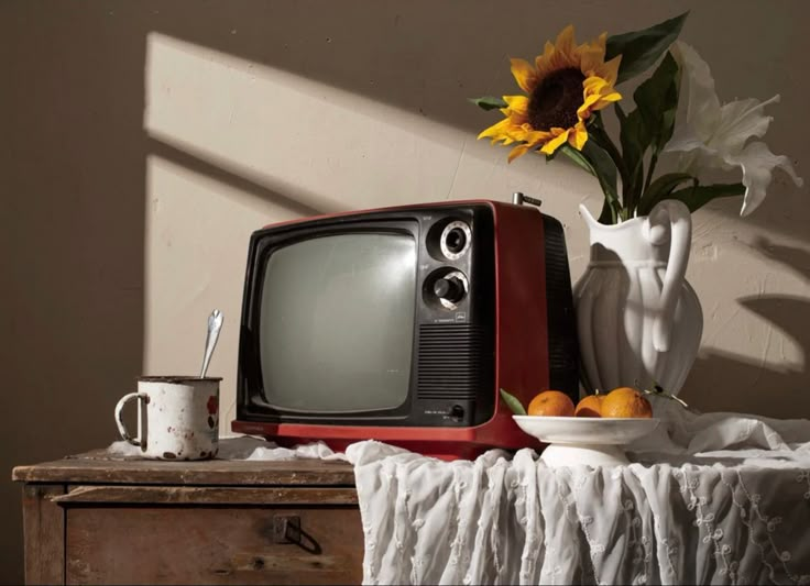 an old tv sitting on top of a table next to a bowl of fruit