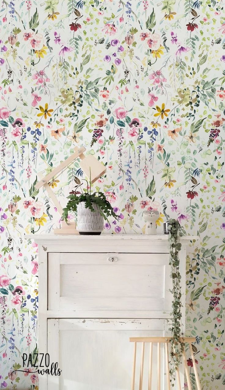 a white piano sitting in front of a wall with flowers painted on the wall behind it