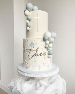 a three tiered cake with blue and white decorations on the top is adorned with a cross