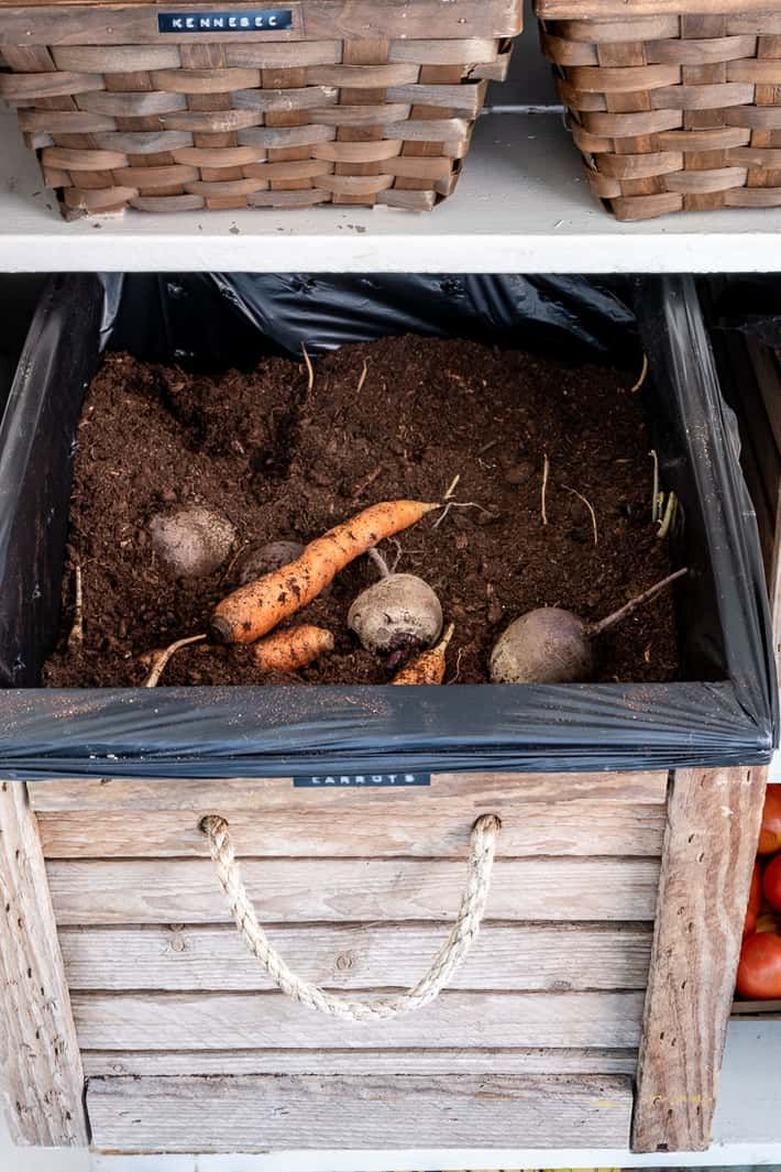 two baskets filled with carrots and potatoes on top of a shelf next to each other