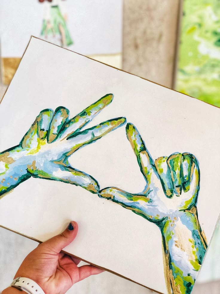 a person holding up a piece of art that looks like two hands reaching out to each other