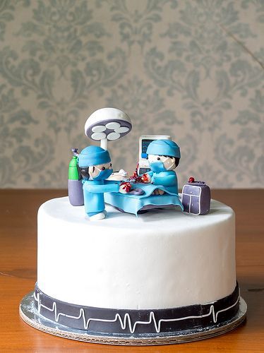 a cake with two doctors sitting on top of it