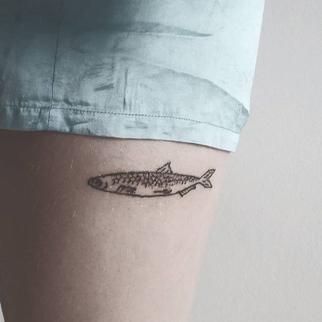 a small fish tattoo on the thigh