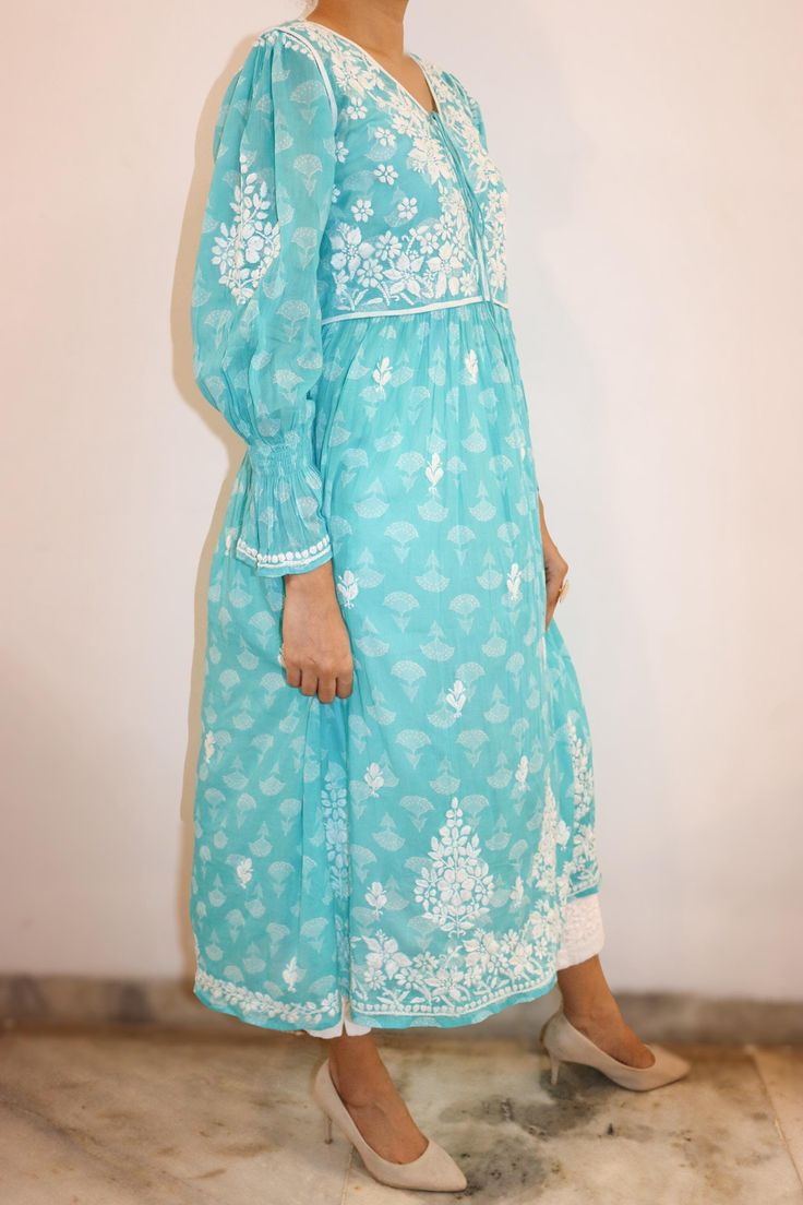 Radiate sophistication in the Malaha Mulmul Printed Dress! Crafted with meticulous attention to detail, it boasts a refined bodice and armholes bordered in crisp white piping. Adorned with intricate chikankari hand embroidery, it exudes timeless elegance.  Complete with full sleeves featuring charming smocking detail at the hem, this dress is a testament to impeccable style. Length - 48 inches Size -  S - fits bust 34 M - fits bust 36 L -fits bust 38 XL - fits bust 40 0X - fits bust 42 1X - fits bust 44 Prewashed . Preshrunk. Elegant Cotton Dress With Cutwork Details, Cotton Wedding Dress With Cutwork, Wedding Cotton Dress With Cutwork Details, Wedding Cotton Dress With Cutwork, Elegant Fitted Dress With Embroidered Border, Embroidered Chikankari Straight Kurta Dress, Fitted Cotton Embroidered Dress With Chikankari, Fitted Cotton Dress With Chikankari Embroidery, Fitted Dresses With Intricate Embroidery In Straight Kurta Style