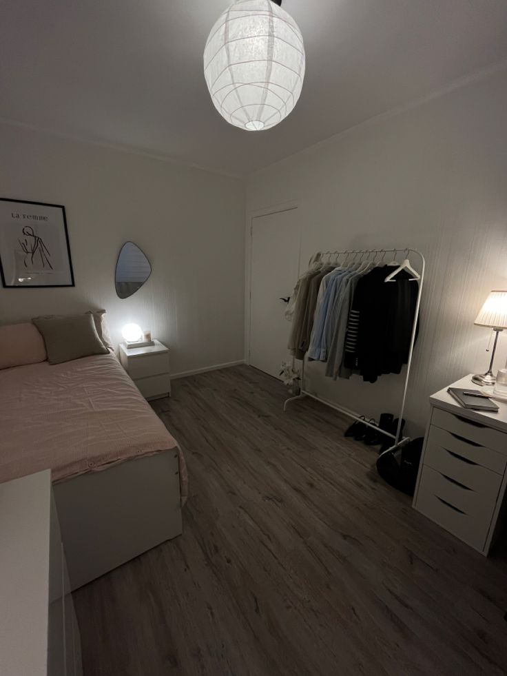 a bedroom with a bed, dresser and mirror in the corner next to a lamp