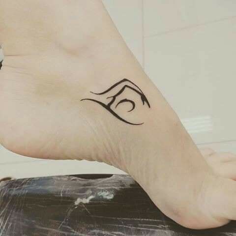 a woman's foot with a tattoo on the top of her leg and an eye in the middle