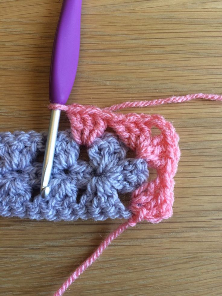 a crocheted object is laying on a table with a purple ball of yarn next to it