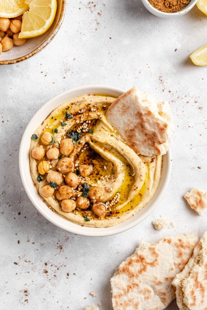 a bowl filled with hummus next to some pita bread